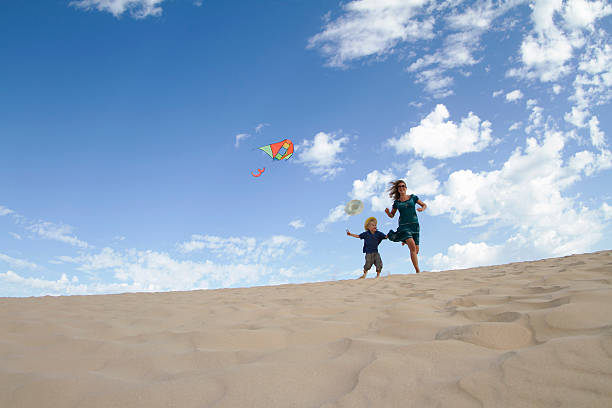 mutter und sohn fliegen kite am strand - @jackstar stock-fotos und bilder