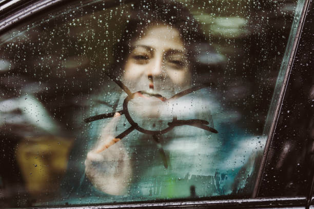 istock Woman drawing sun on car window during rainy day. 1436912433