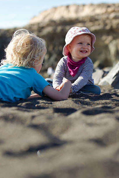 boy playing with sibling on beach - babies and children cheerful low angle view vertical стоковые фото и изображения