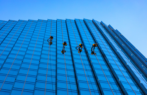 Warsaw, Poland - July 3, 2022: Skyscraper high altitude facade cleaning crew on glass facing of Mennica Legacy Tower plaza at Prosta street in Wola business district of city center