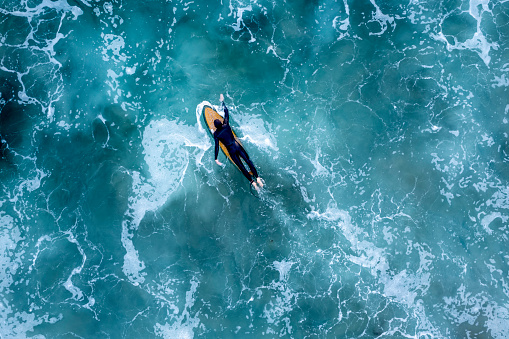 Overhead drone shot of a surfer in the wavy sea, Newport Beach, California, USA