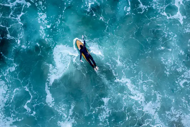 An overhead drone shot of a surfer in the wavy sea, Newport Beach, California, USA