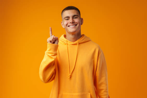istock Handsome young man pointing to copy space on a yellow background 1436914637