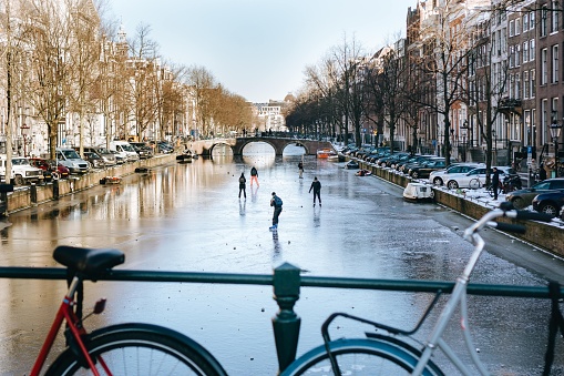 A bike on a bridge with children on the background Ice skating on the frozen canal in Amsterdam