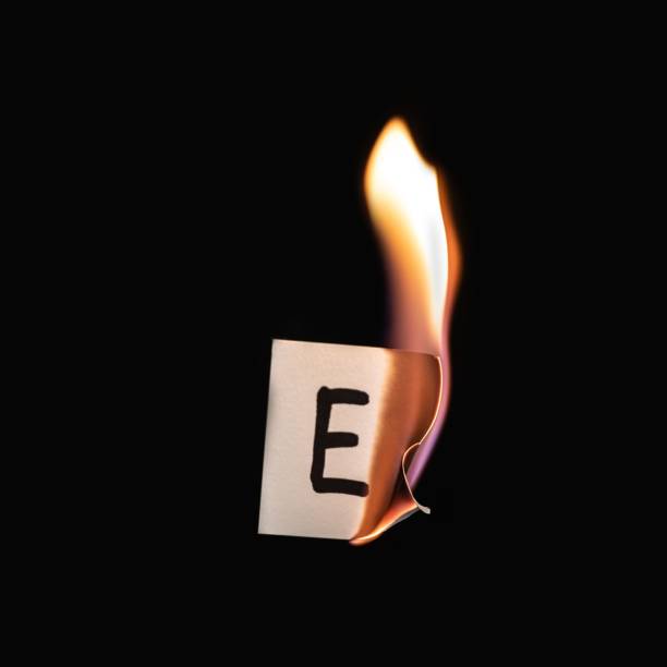 istock Small paper with letter E burning on a black background 1436916715