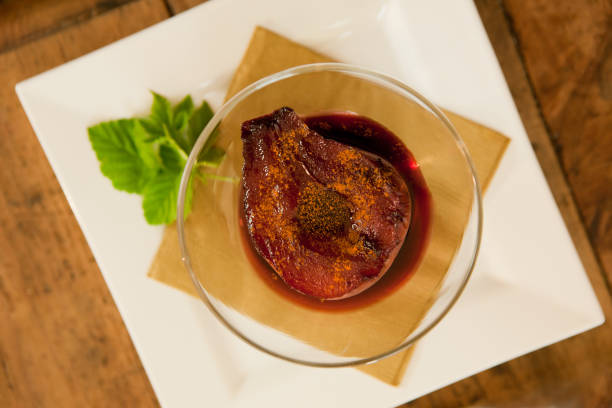 Delicious pear poached in red wine served with sauce on white plate