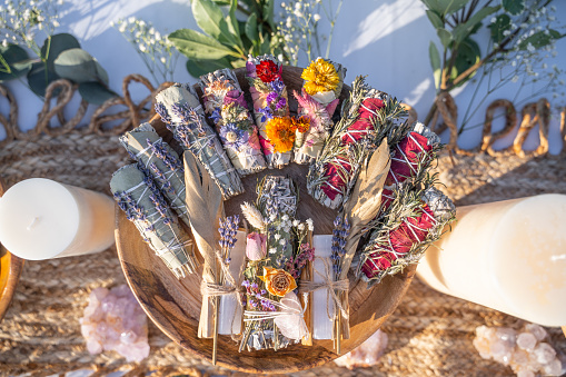 A top view of smudging sticks with dried flowers on a wooden tray