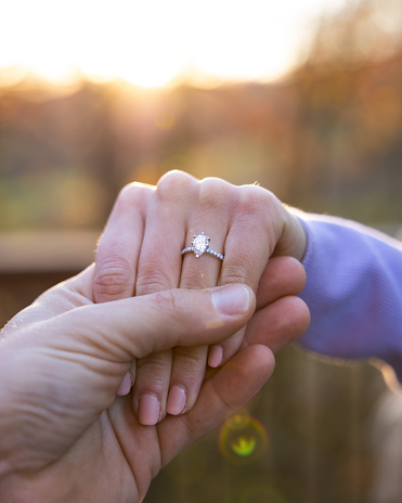A closeup of the man's hand holding the girl's hand with a ring.