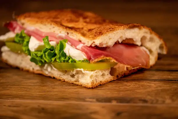 A stuffed focaccia with cold cuts and vegetables on a wooden surface