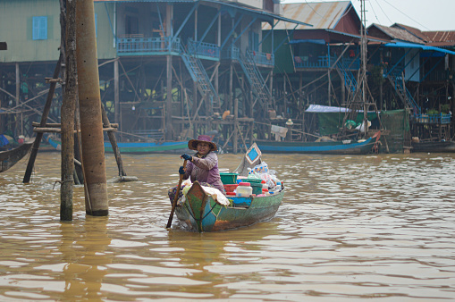 Siem Reap, Cambodia – October 21, 2020: An old Cambodian person in an old wooden canoe on the Tonle Sap Lake in Siem Reap, Cambodia