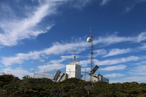 A scenic view of a radio tower found on the peak of a mountain