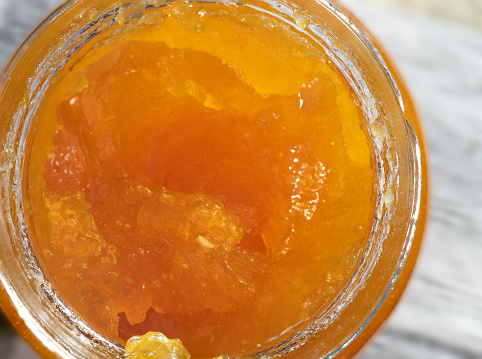A top view of a glass jar with orange marmalade