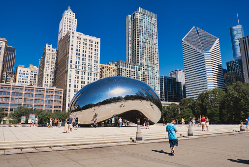 Chicago, United States – June 12, 2021: A warm sunny day in Millennium Park, Illinois with the famous Bean sculpture surrounded by skyscrapers