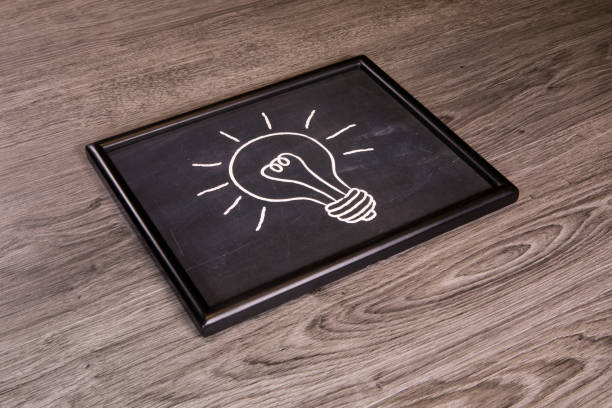 An idea icon on chalkboard, blackboard over a gray wood background