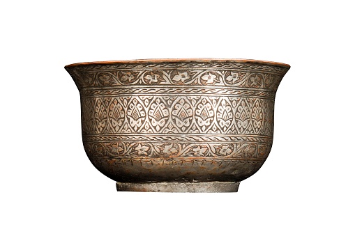 An antique metal bowl with artistic chasing and engraving on a white background