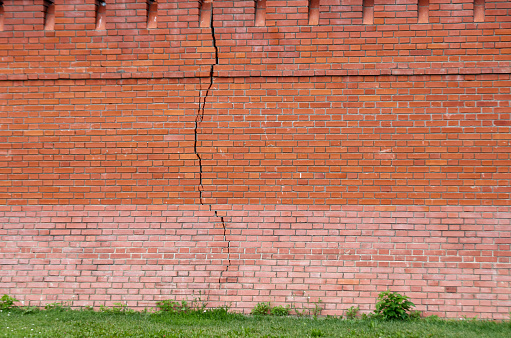 Long vertical crack in a red brick wall