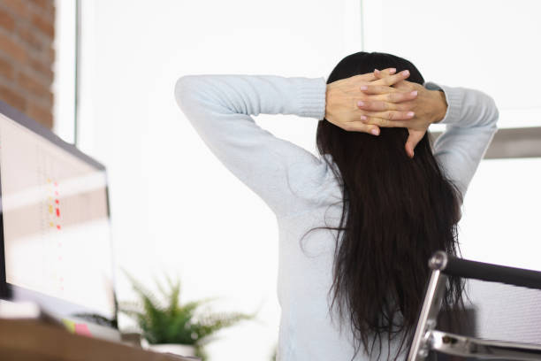 Woman putting her hands behind head at table in office