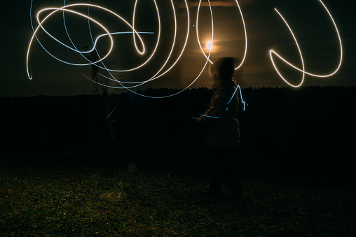 drawing with light at night against the background of the moon