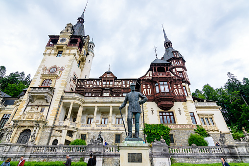 Sinaia, Romania - 3 July 2021: Beautiful neo-Renaissance building of Peles Castle (Castelul Peles) near Bucegi Mountains (Muntii Bucegi) in a cloudy summer day in Sinaia town