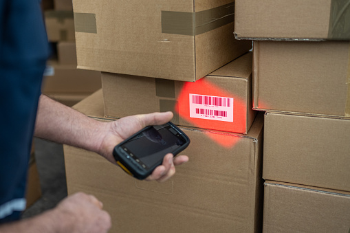 Delivery person scanning packages outside delivery van.