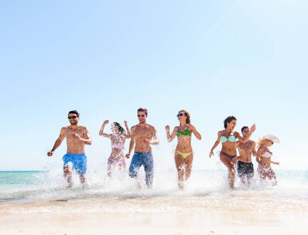 istock Cheerful friends having fun while running through sea in summer day. 1436929220