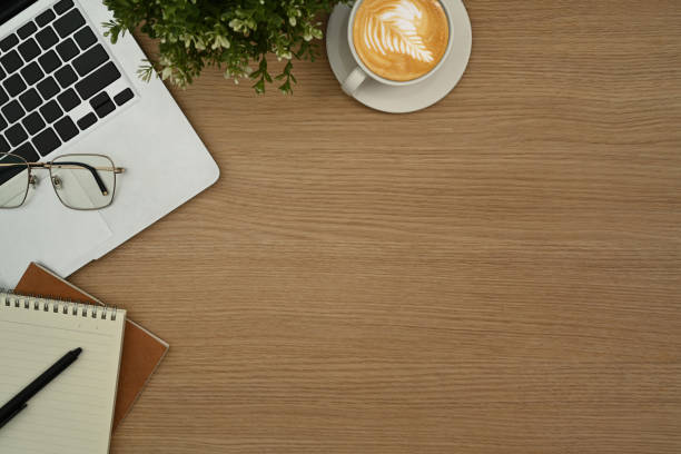 istock Top view laptop computer, coffee cup, notepad and houseplant on wooden background. Copy space for your text. 1436931705