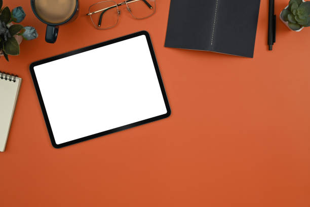 istock Mock up digital tablet with blank screen, eyeglasses, notepad and coffee cup on orange background. 1436931709