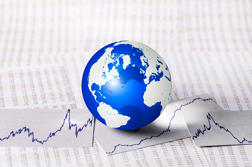 Globus mit Kurstabellen und Kurven als Symbol für die Entwicklung der Märkte