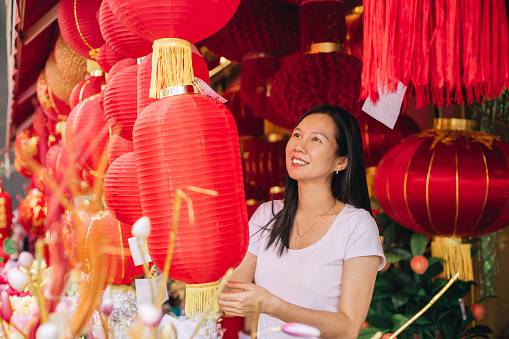 Asian woman choosing colourful decorations for Chinese New Year in celebration of luck, healthiness, happiness, reunion and prosperities