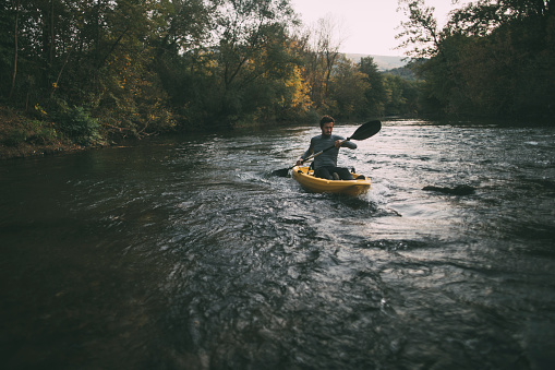 Man paddling kayak on river. Whitewater kayaking.