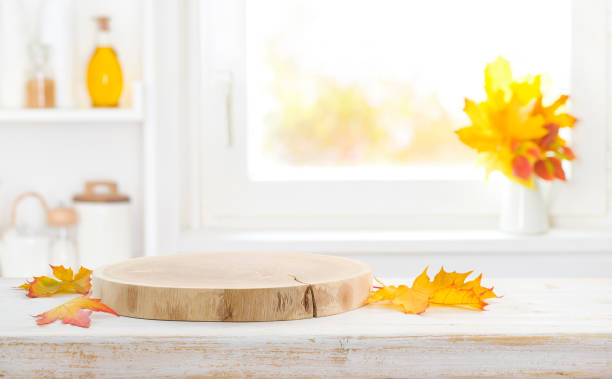 Wooden pedestal and faded autumn leaves on empty kitchen table stock photo