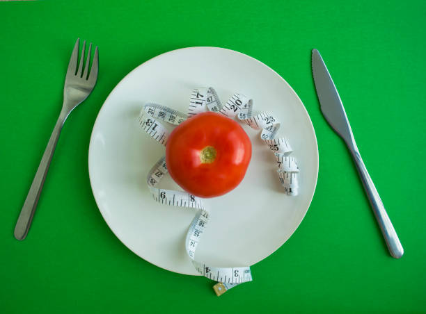 istock Tomato and centimeter tape in a plate, fork and knife 1436941755
