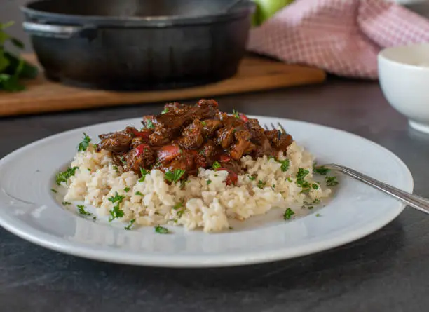 Healthy and low fat beef stew with vegetables and brown rice. Served ready to eat on a plate on kitchen table background