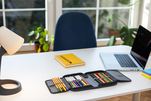 Laptop, pencil case, backpack and school supplies on the desk, in the room