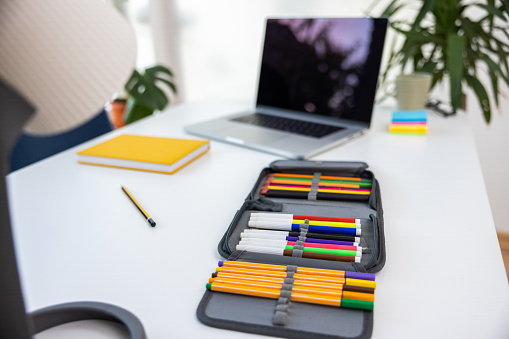 Laptop, pencil case, backpack and school supplies on the desk, in the room