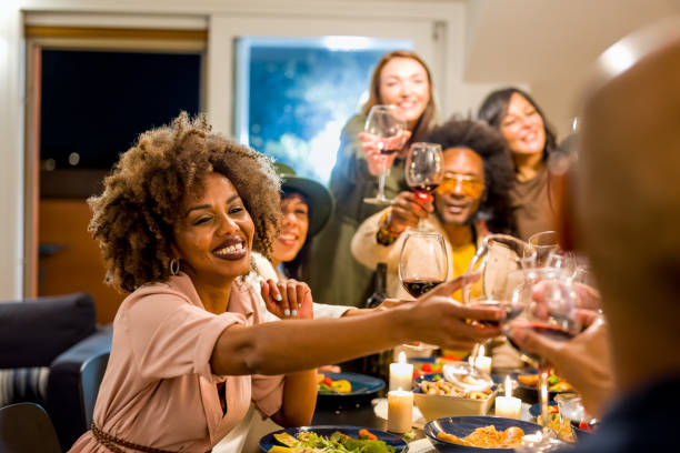 altersgemischte gruppe von freunden, die auf der dinnerparty anstoßen, fokus auf das gesicht der frau, brasilianer, die rotwein trinken und veganes essen essen, glückliches familien-chering und toasting - women mature adult black american culture stock-fotos und bilder