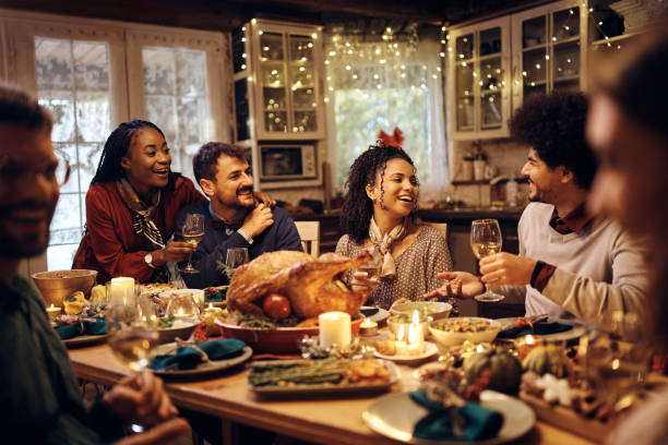 gruppo multirazziale di amici che si divertono mentre parlano durante la cena del ringraziamento a tavola. - stuffed turkey foto e immagini stock