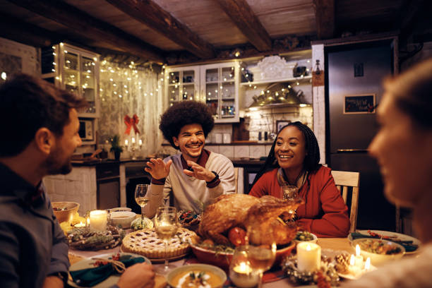 istock Young happy friends enjoying in conversation during Christmas dinner at dining table. 1436949572