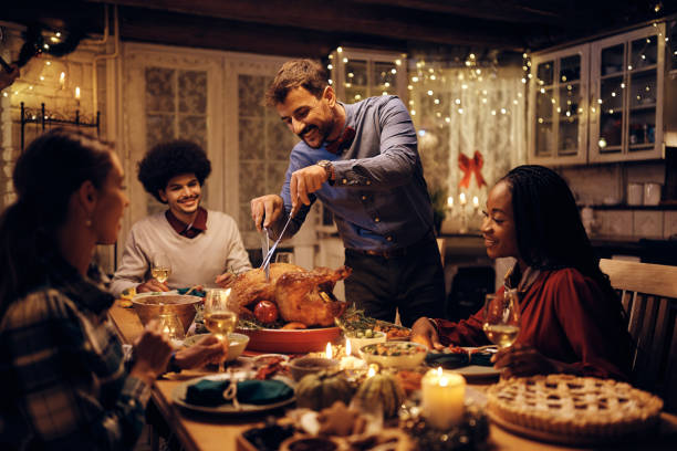 istock Happy man carving roast turkey while having dinner with friends on Thanksgiving. 1436949588