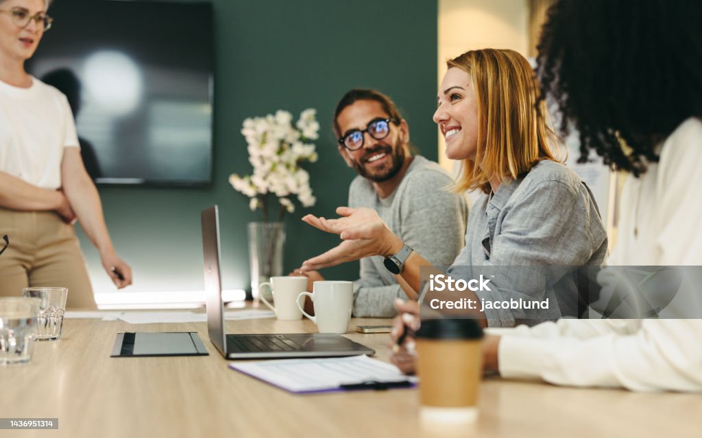 Business woman talking to her colleagues during a meeting in a boardroom Business woman talking to her colleagues during a meeting in a boardroom. Group of happy business people working together in a creative office. Office Stock Photo