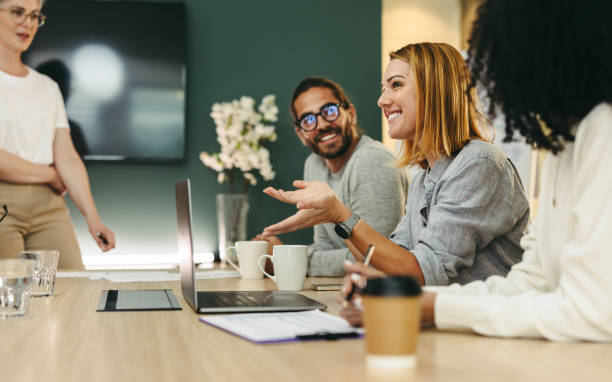 Business woman talking to her colleagues during a meeting in a boardroom Business woman talking to her colleagues during a meeting in a boardroom. Group of happy business people working together in a creative office. communication stock pictures, royalty-free photos & images