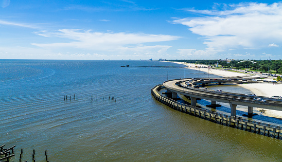 An aerial view of ruins of an old pier in Biloxi under a blue cloudy sky on a sunny day