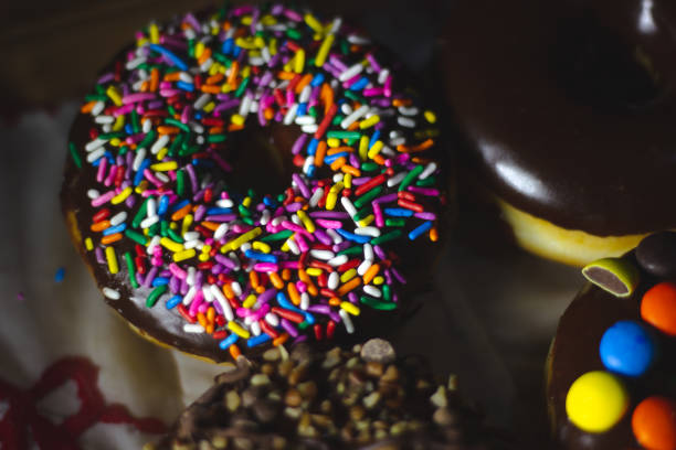Delicious donuts with chocolate glaze and different toppings - sprinkles, chocolate chip, candies