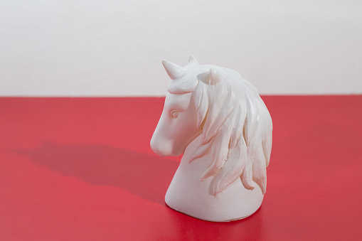 A closeup shot of a white horse head figurine on a red surface