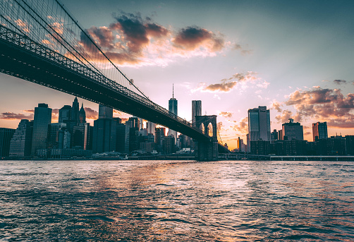 A majestic view of the cable-stayed Brooklyn Bridge and New York City skyline with modern high-rise buildings at twilight