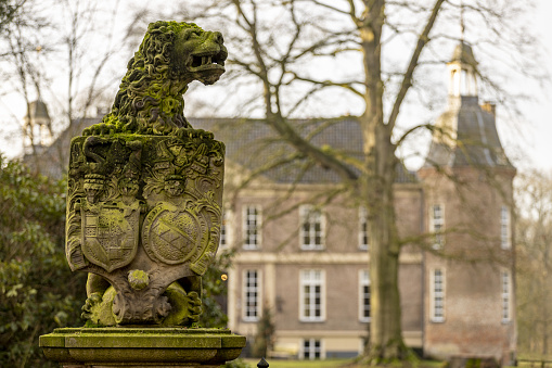 Vorden, Netherlands – January 08, 2021: Lion holding coat of arms at the entrance to the Hackfort castle seen out of focus in the background