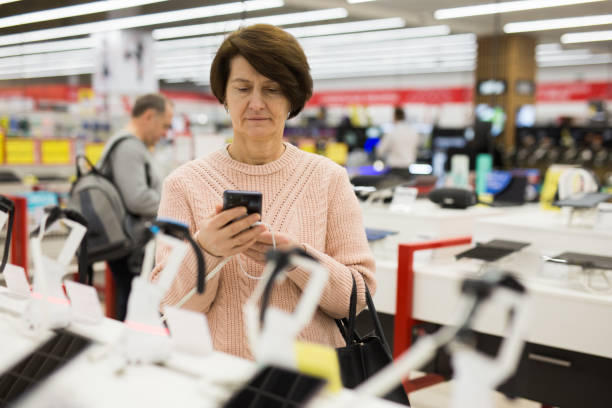 istock European woman attentive selects a mobile phone 1436960968