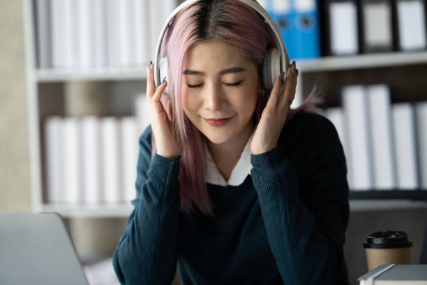 istock A young female student sitting at the table, using headphone when studying. 1436961147