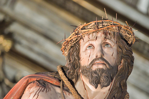 A crown of thorns and a palm leaf on burlap, representing the Good Friday and Palm Sunday holidays.