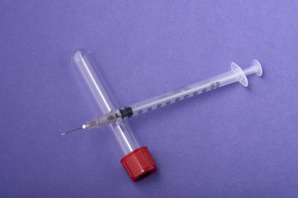 istock Top view of a syringe needle with a COVID-19 test on a purple surface 1436962006